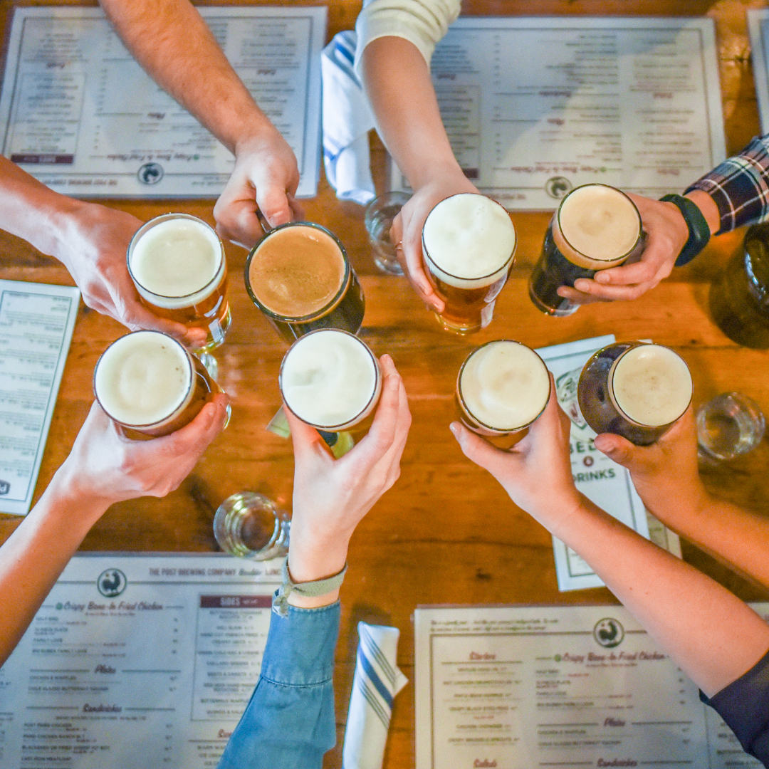 hands cheersing beer glasses over a table