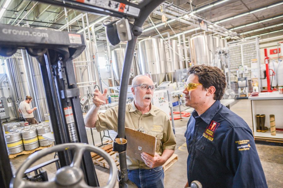 brewery workers conversing next to forklift