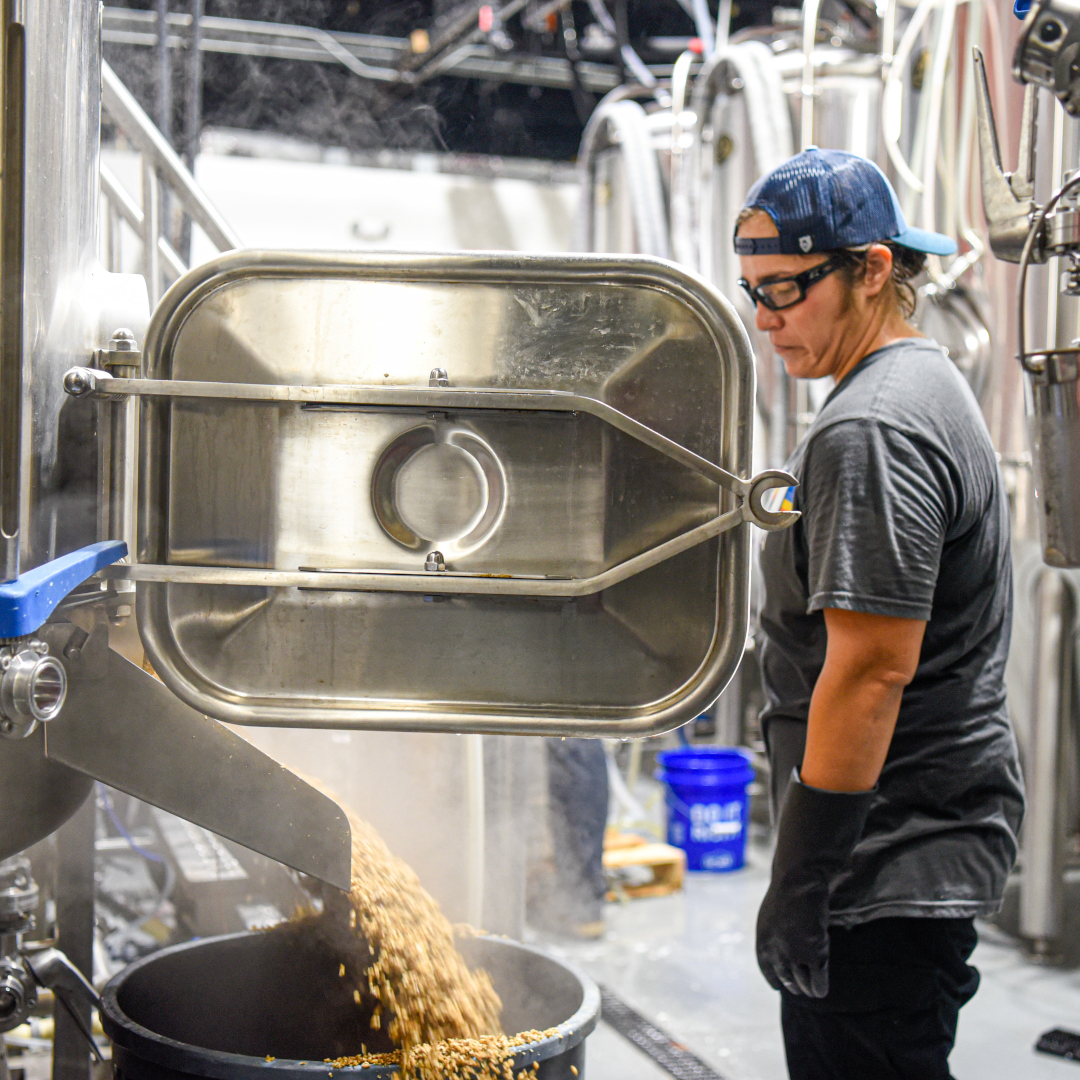 brewery worker removing spent grain from mash tun