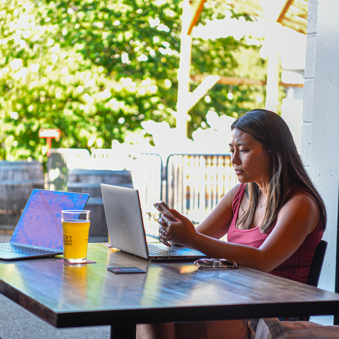 brewery professional using laptop and phone with a beer