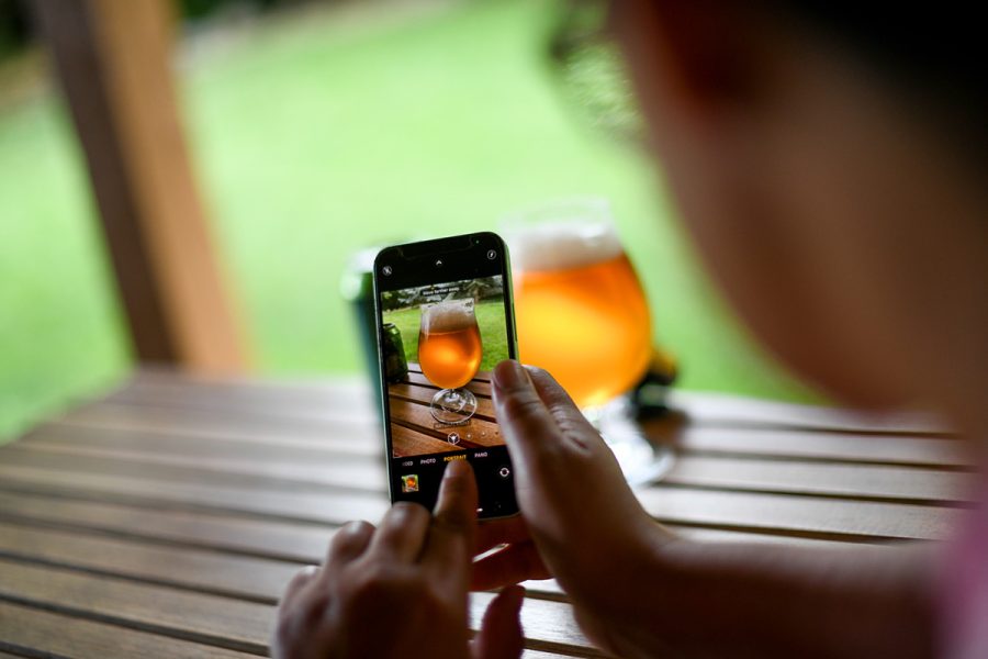 person photographing beer on a smart phone