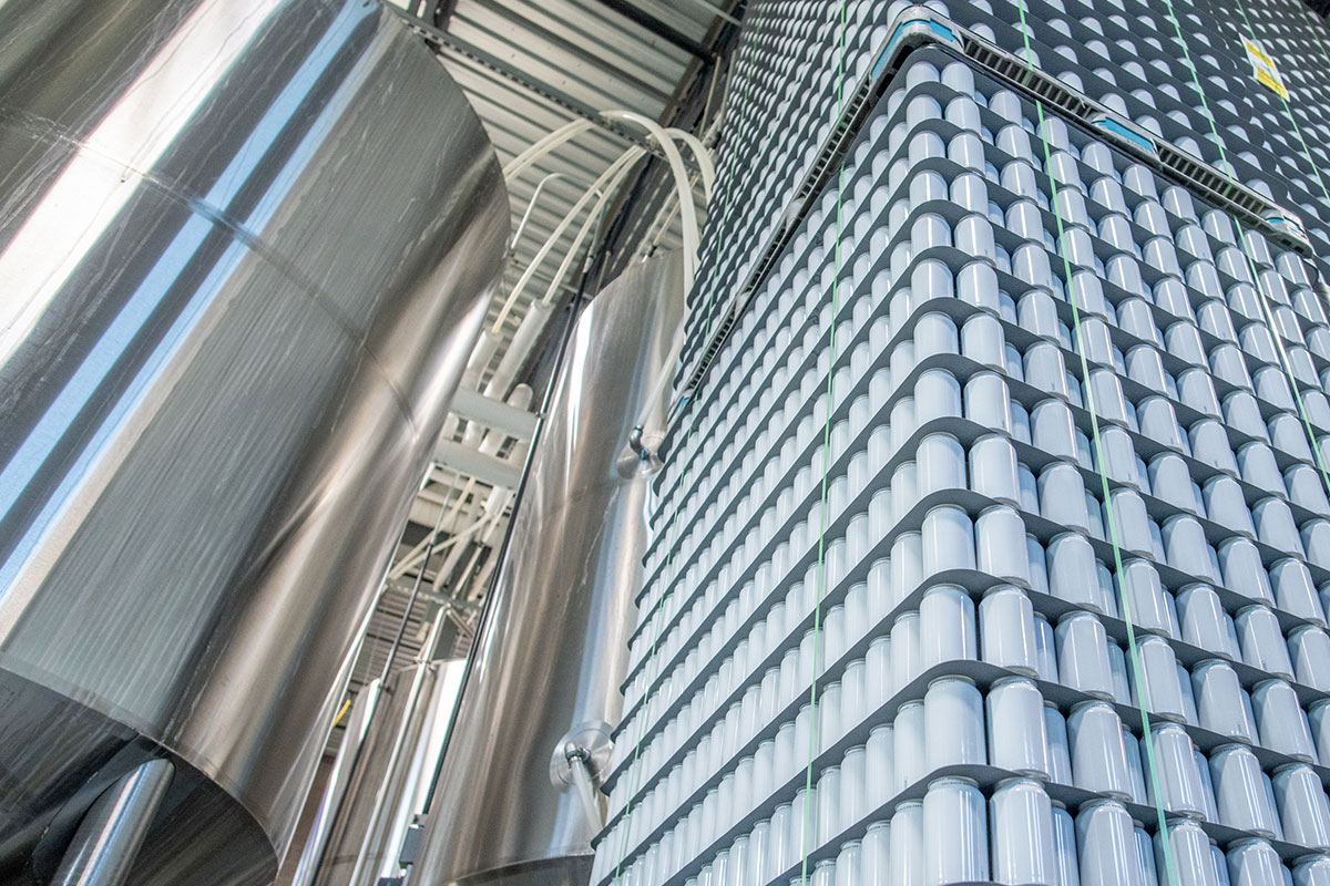 steel brewing equipment and stacks of aluminum cans